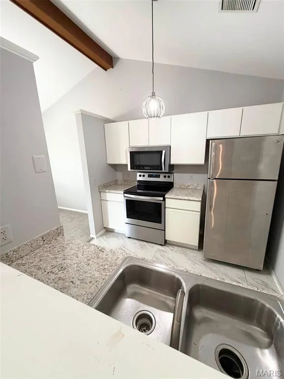 Kitchen featuring stainless steel appliances, white cabinetry, granite-style countertops, dual basin sink, and vaulted ceiling with exposed beam — 974 Windstream Drive #38, St Peters, MO 63376