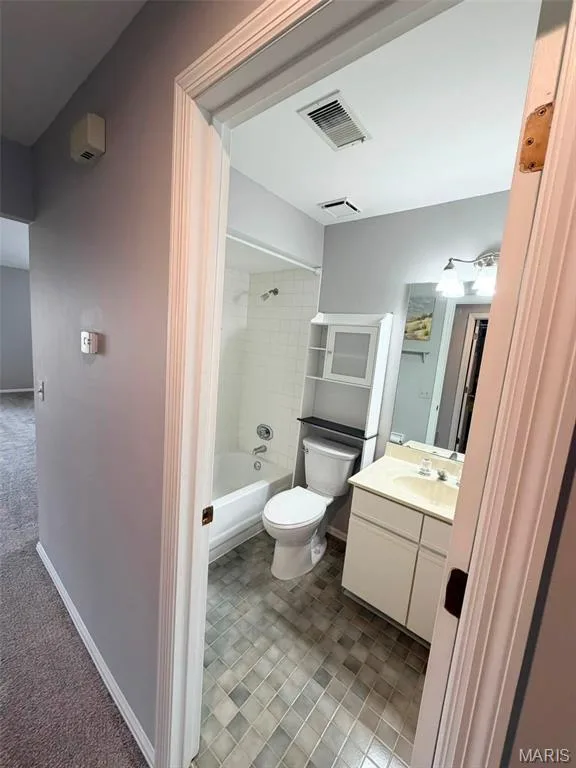 Tub/shower combination with white subway tile surround, tile flooring, white vanity with integrated sink, and wall-mounted storage cabinet — 974 Windstream Drive #38, St Peters, MO 63376