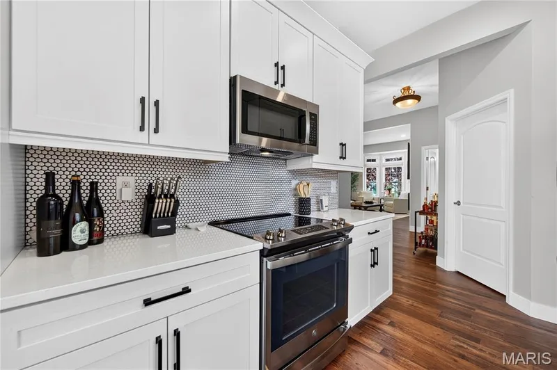 Contemporary kitchen featuring white shaker cabinetry with dark hardware, a stainless steel microwave, and an electric range — 2514 S Larksong Drive, Grover, MO 63040