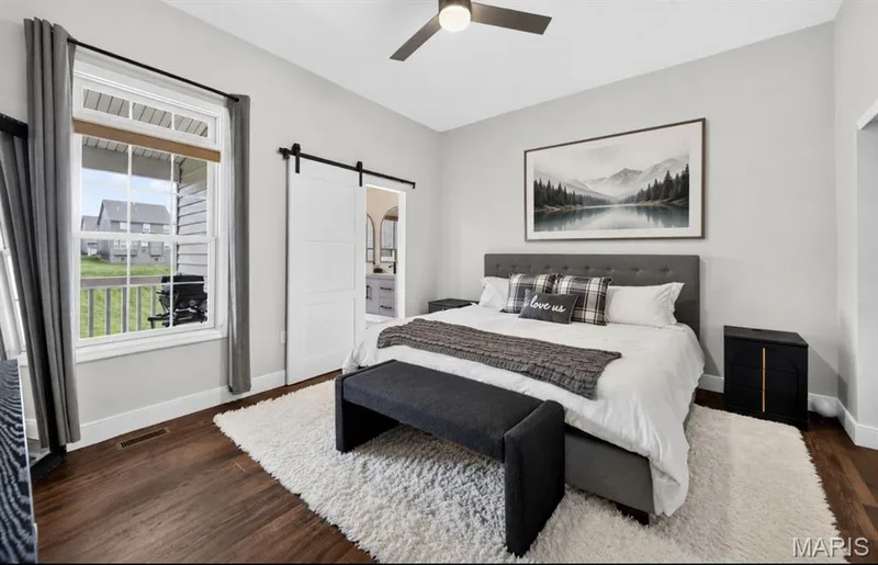 Primary Bedroom featuring wood-finish flooring, a ceiling fan, and a large window — 2514 S Larksong Drive, Grover, MO 63040