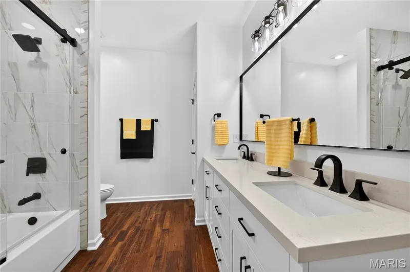 Dual vanity featuring white cabinetry with dark hardware and light countertops — 2514 S Larksong Drive, Grover, MO 63040