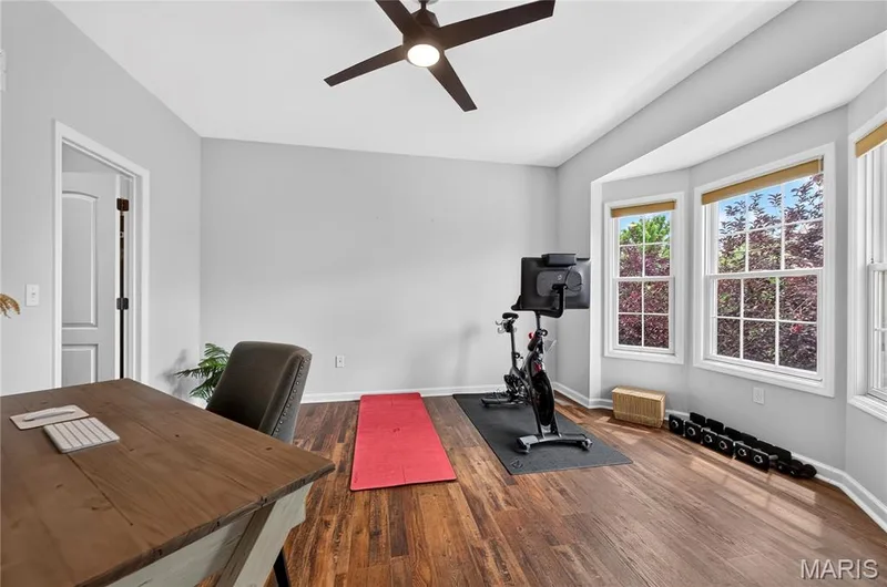Versatile room with wood-finish flooring, a contemporary ceiling fan, and a bay window featuring three large windows — 2514 S Larksong Drive, Grover, MO 63040