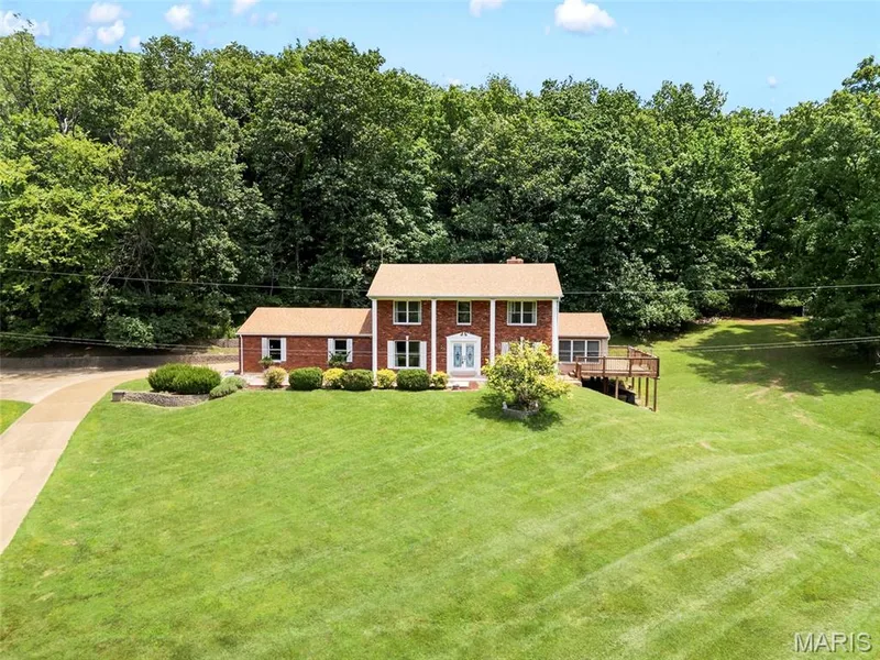 Traditional brick residence with a prominent front facade, white column accents, and a light-colored shingle roof — 3672 Hawks Rest Road, Wildwood, MO 63069