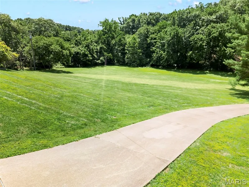 Expansive green space featuring a curved concrete path and mature perimeter trees — 3672 Hawks Rest Road, Wildwood, MO 63069