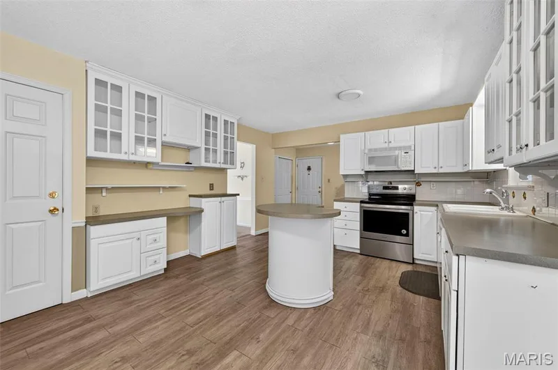 Kitchen featuring wood-finish flooring, white cabinetry, gray countertops, and stainless steel appliances — 3672 Hawks Rest Road, Wildwood, MO 63069