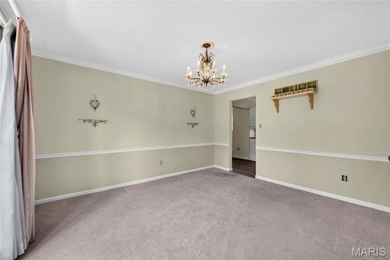 Carpeted interior space featuring a chandelier, crown molding, chair rail molding, and a built-in wall shelf — 3672 Hawks Rest Road, Wildwood, MO 63069