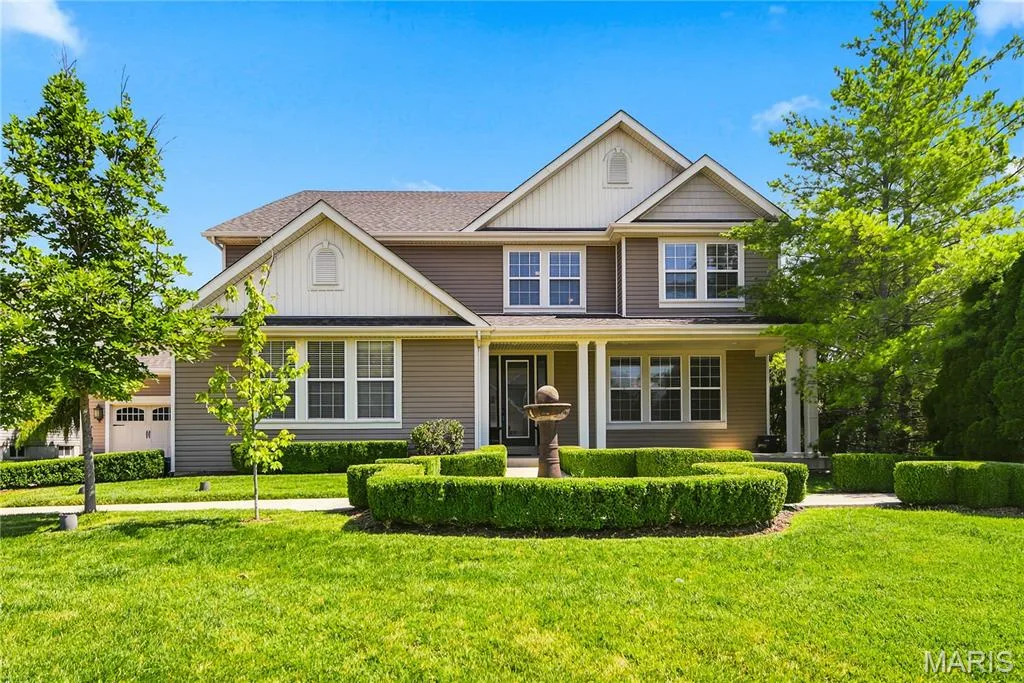 Beautifully landscaped two-story home featuring a welcoming large front porch — 5500 Wooded Creek Drive, O'Fallon, MO 63304