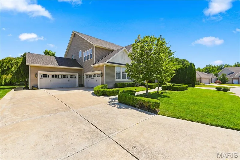 Side of house showcasing the four car garage with plenty of room for additional parking on the concrete driveway — 5500 Wooded Creek Drive, O'Fallon, MO 63304