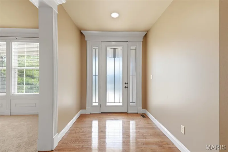 Double entry door with frosted sidelights, hardwood-finish flooring, and crown molding accents — 5500 Wooded Creek Drive, O'Fallon, MO 63304