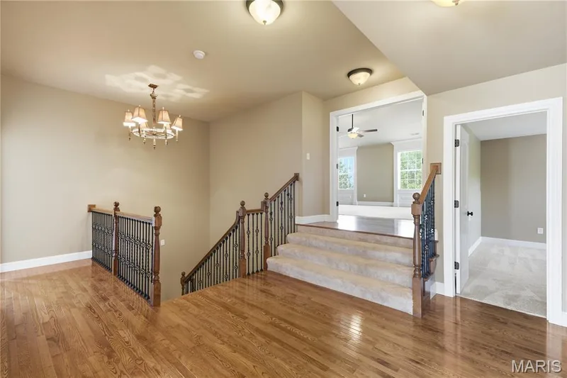 Upper hallway with hardwood and steps leading up to the owners suite — 5500 Wooded Creek Drive, O'Fallon, MO 63304
