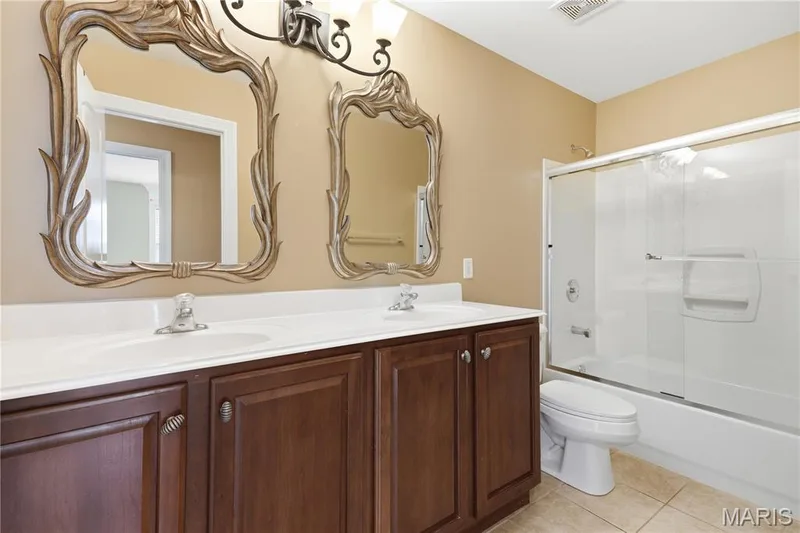 Hall bath with double vanity and decorative mirrors — 5500 Wooded Creek Drive, O'Fallon, MO 63304