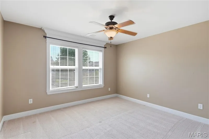 Neutral paint palette, ceiling fan, white trim, twin windows with blinds, and light-toned carpeting — 5500 Wooded Creek Drive, O'Fallon, MO 63304
