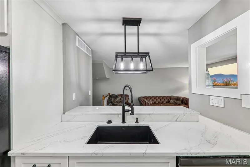 Kitchen peninsula featuring a black undermount sink, gooseneck faucet, and light-toned, veined countertops — 16180 Lea Oak Court, Chesterfield, MO 63017