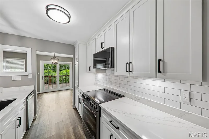 Modern kitchen featuring white shaker cabinetry, white subway tile backsplash, and light-toned countertops — 16180 Lea Oak Court, Chesterfield, MO 63017