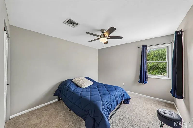 Carpeted room featuring light gray walls, a ceiling fan with light fixture, and a white-framed window — 16180 Lea Oak Court, Chesterfield, MO 63017