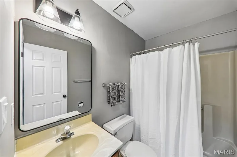 Bathroom featuring a vanity with an integrated sink, framed mirror, and two-light fixture — 16180 Lea Oak Court, Chesterfield, MO 63017