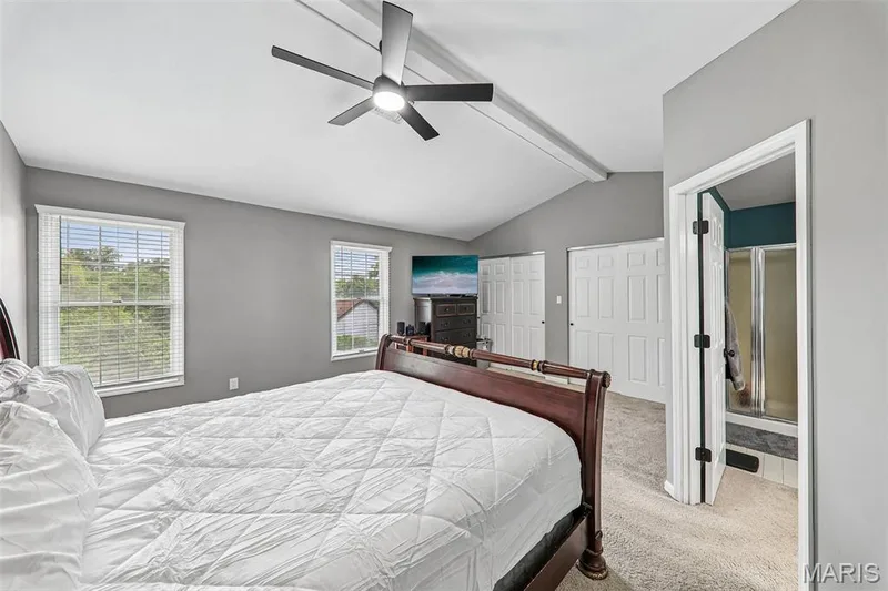Vaulted ceiling bedroom featuring a contemporary ceiling fan, dual windows with blinds, and light-colored carpeting — 16180 Lea Oak Court, Chesterfield, MO 63017