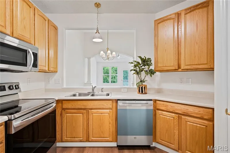 Kitchen featuring wood cabinetry, light countertops, and stainless steel appliances — 704 Harrier Drive #V, Lake St. Louis, MO 63367
