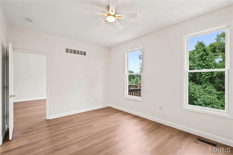 Spacious room featuring wood-finish flooring and a ceiling fan with light fixture — 704 Harrier Drive #V, Lake St. Louis, MO 63367