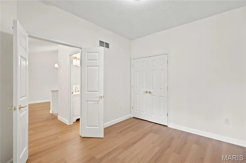 Bright interior space featuring wood-finish flooring, white walls, and a recessed ceiling light — 704 Harrier Drive #V, Lake St. Louis, MO 63367