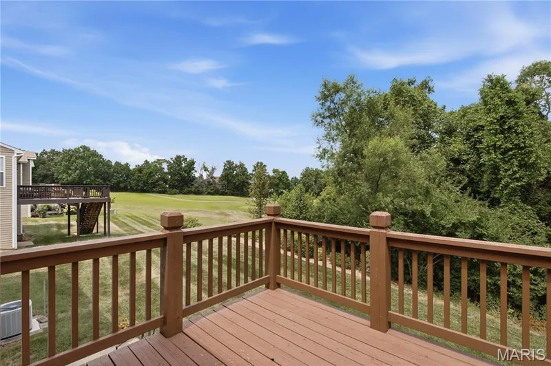 Expansive outdoor deck featuring wood-finish flooring and a full wood railing system — 704 Harrier Drive #V, Lake St. Louis, MO 63367