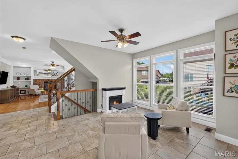 The Hearth Room has tile flooring, electric fireplace that will stay with the home, and a wall of cased windows with transoms overlooking the back yard. — 31 Pinewood Court, Dardenne Prairie, MO 63368