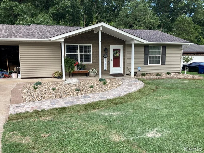 Ranch-style exterior with beige siding, a dark asphalt shingle roof, and a red front door — 802 Barbara Place, O'Fallon, MO 63366