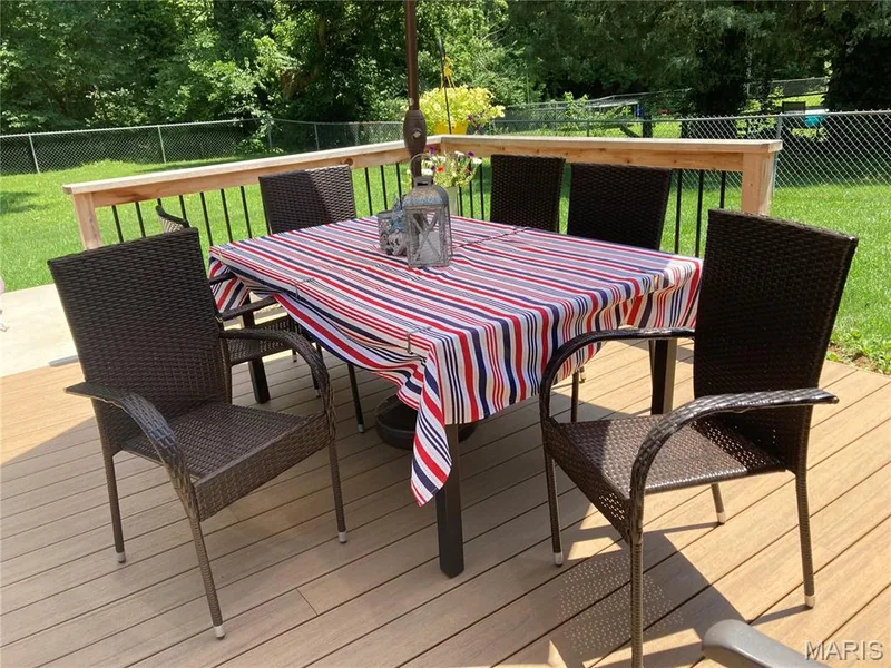 Spacious outdoor deck featuring wood-finish composite decking and a light wood railing with black balusters — 802 Barbara Place, O'Fallon, MO 63366