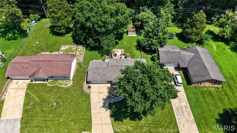 Aerial perspective highlighting a residential property with a multi-car driveway, an attached garage, and a lush green lawn — 802 Barbara Place, O'Fallon, MO 63366