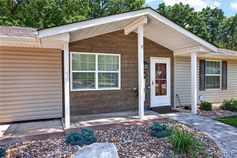 Inviting entry with a covered porch, white paneled door, and exterior lighting — 802 Barbara Place, O'Fallon, MO 63366