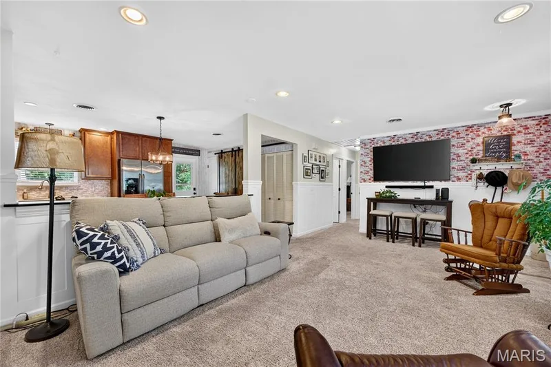 Expansive living area featuring textured carpeting, white wainscoting, and recessed lighting — 802 Barbara Place, O'Fallon, MO 63366