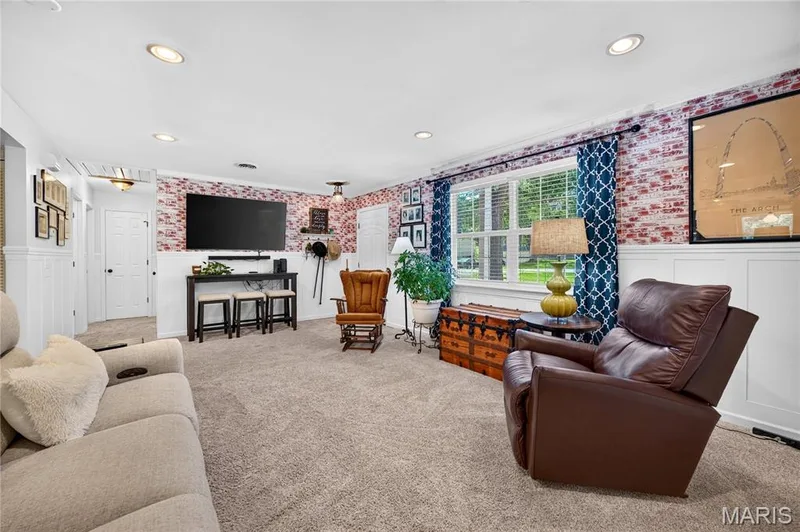 Spacious interior featuring recessed lighting, a window with horizontal blinds, and a distinctive accent wall with brick-finish detailing — 802 Barbara Place, O'Fallon, MO 63366