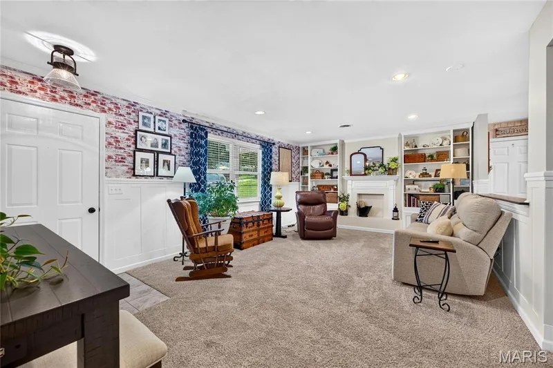 Spacious living area featuring exposed brick detailing, white wainscoting, and large windows — 802 Barbara Place, O'Fallon, MO 63366