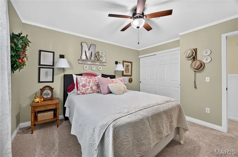 Bedroom featuring a ceiling fan with integrated lighting, crown molding, and neutral-toned carpeting — 802 Barbara Place, O'Fallon, MO 63366