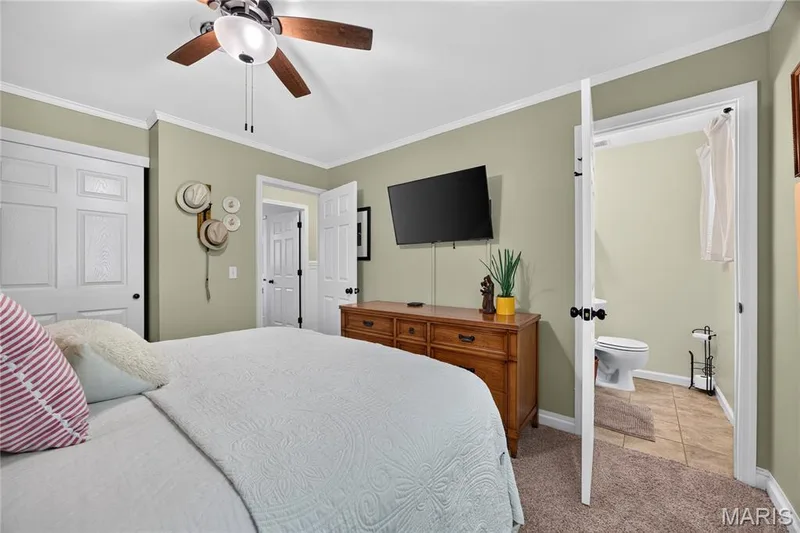 Carpeted sleeping area featuring a ceiling fan with light fixture, light green wall tones, and white trim — 802 Barbara Place, O'Fallon, MO 63366