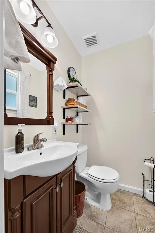 Bathroom featuring a vanity with a white basin sink, polished chrome faucet, and a dark wood-finish cabinet — 802 Barbara Place, O'Fallon, MO 63366