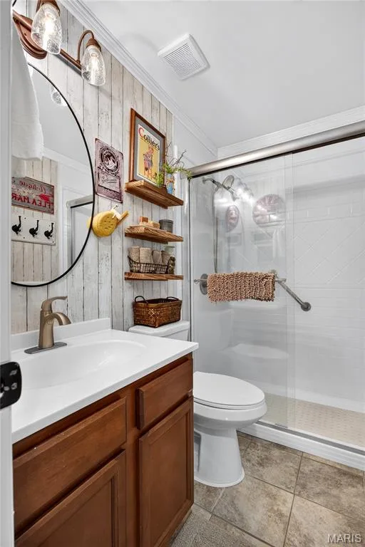 Bathroom featuring a shower with glass enclosure, single vanity with a white countertop and bronze-finish faucet, and plank-style wall paneling — 802 Barbara Place, O'Fallon, MO 63366
