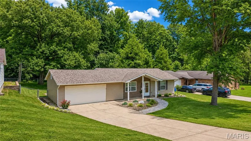 Ranch-style residence featuring a two-car garage, concrete driveway, and a stone-lined walkway leading to the entry — 802 Barbara Place, O'Fallon, MO 63366