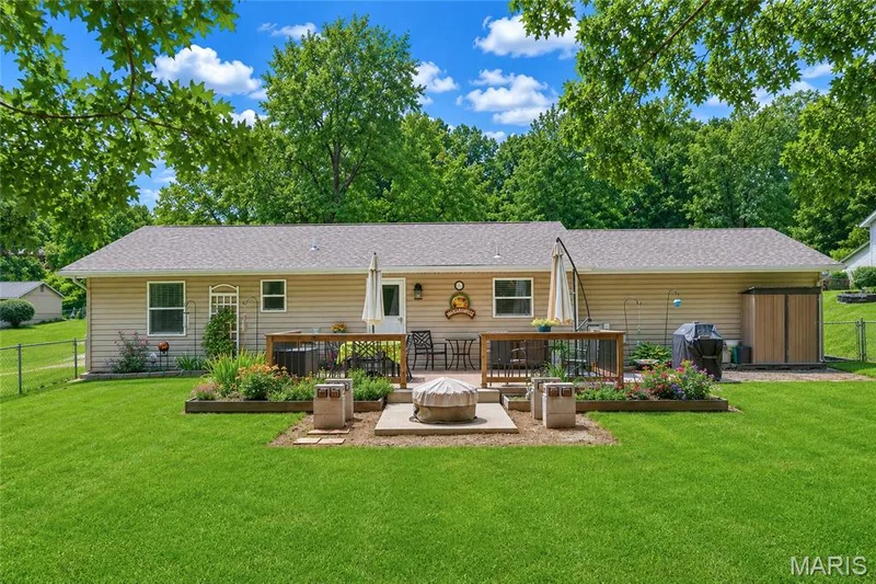 Expansive green lawn with a composite deck featuring a fire pit area — 802 Barbara Place, O'Fallon, MO 63366