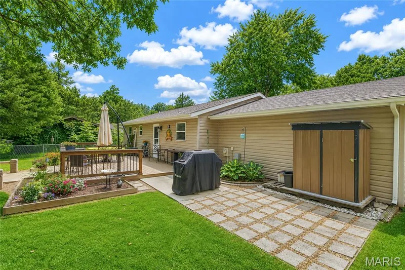 Expansive backyard featuring a multi-level wooden deck, a paver patio, and a built-in garden bed — 802 Barbara Place, O'Fallon, MO 63366