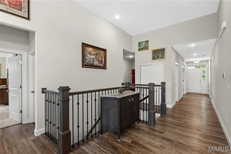 Upper-level hallway with wrought iron staircase railing leads to the primary suite to the left. — 1316 Silver Fern Drive, Lake St. Louis, MO 63367