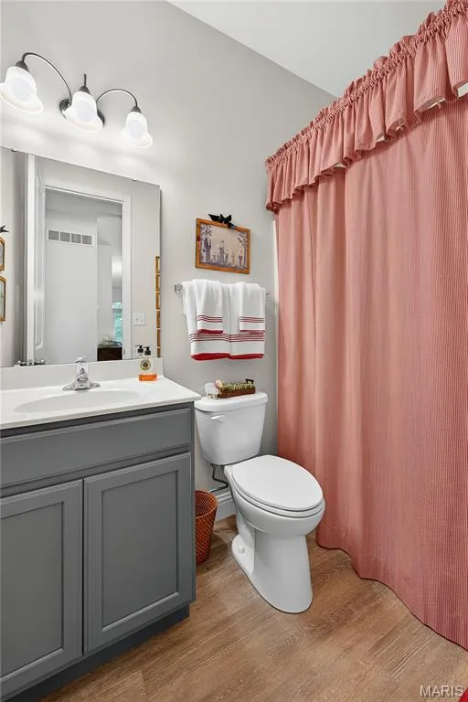 The Hall Bath has the same Luxury Vinyl Wood Plank Floor as the Main Living areas, Tall Wood Vanity, Tall Elongated Toilet & Tub/Shower with Shelves! — 6170 Suntan Drive, St Charles, MO 63301