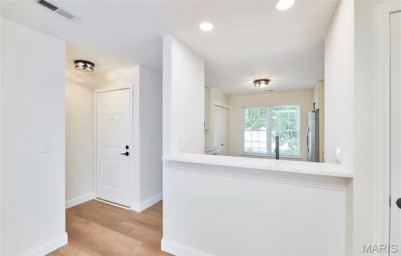 Entryway with wood-finish Luxury vinyl plank flooring and a kitchen pass-through featuring a Quartz countertop — 214 Sugar Lake Drive #5, St Peters, MO 63376