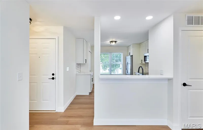Open-concept entryway with wood-finish Luxury vinyl plank flooring, white cabinetry, and recessed lighting — 214 Sugar Lake Drive #5, St Peters, MO 63376