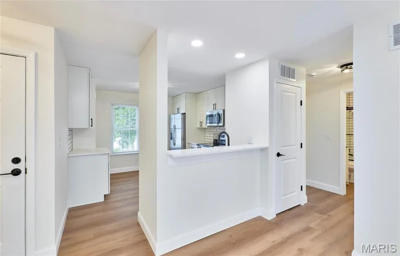 Open-concept entryway with wood-finish Luxury vinyl plank flooring, white cabinetry, and recessed lighting — 214 Sugar Lake Drive #5, St Peters, MO 63376