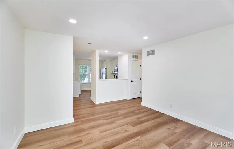 Spacious living room featuring wood-finish Luxury vinyl plank flooring, recessed lighting, and a sliding glass door leading to an outdoor deck — 214 Sugar Lake Drive #5, St Peters, MO 63376