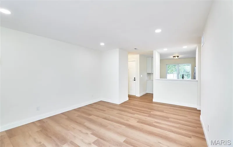 Spacious living room featuring wood-finish Luxury vinyl plank flooring, recessed lighting, and a sliding glass door leading to an outdoor deck — 214 Sugar Lake Drive #5, St Peters, MO 63376