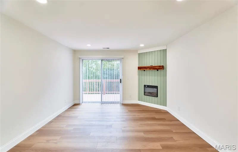 Spacious living room featuring wood-finish Luxury vinyl plank flooring, recessed lighting, and a modern corner fireplace with a shiplap accent wall and wooden mantel — 214 Sugar Lake Drive #5, St Peters, MO 63376