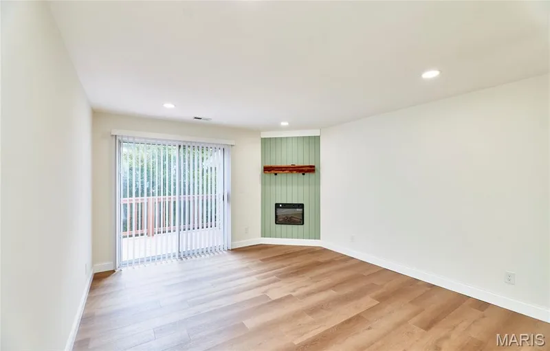 Spacious living room featuring wood-finish Luxury vinyl plank flooring, recessed lighting, and a corner-mounted electric fireplace with a wood mantle and shiplap accent wall — 214 Sugar Lake Drive #5, St Peters, MO 63376