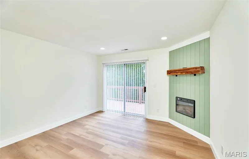 Spacious living room featuring wood-finish Luxury vinyl plank flooring, recessed lighting, and a sliding glass door leading to an outdoor deck — 214 Sugar Lake Drive #5, St Peters, MO 63376